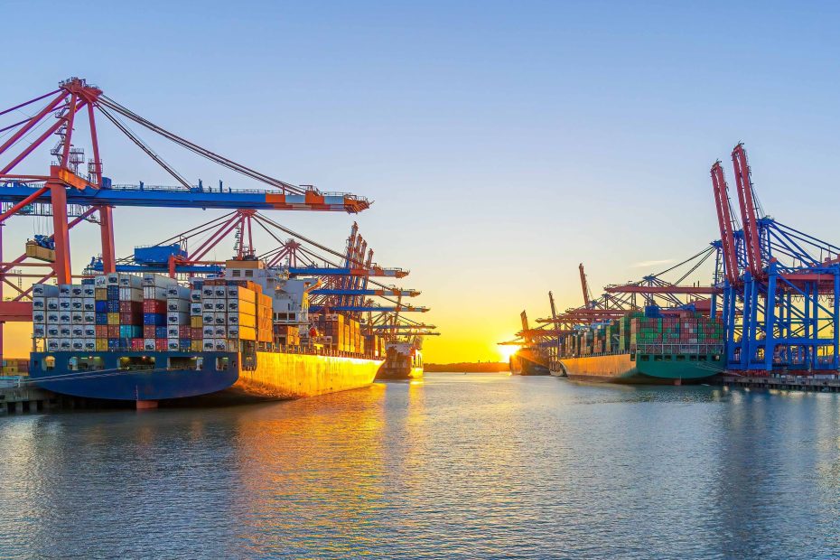 global trade disruption 2025_geo-trends.eu_Cargo ships docked at a port during sunset, reflecting Maersk’s outlook on strong demand and global trade disruptions in 2025
