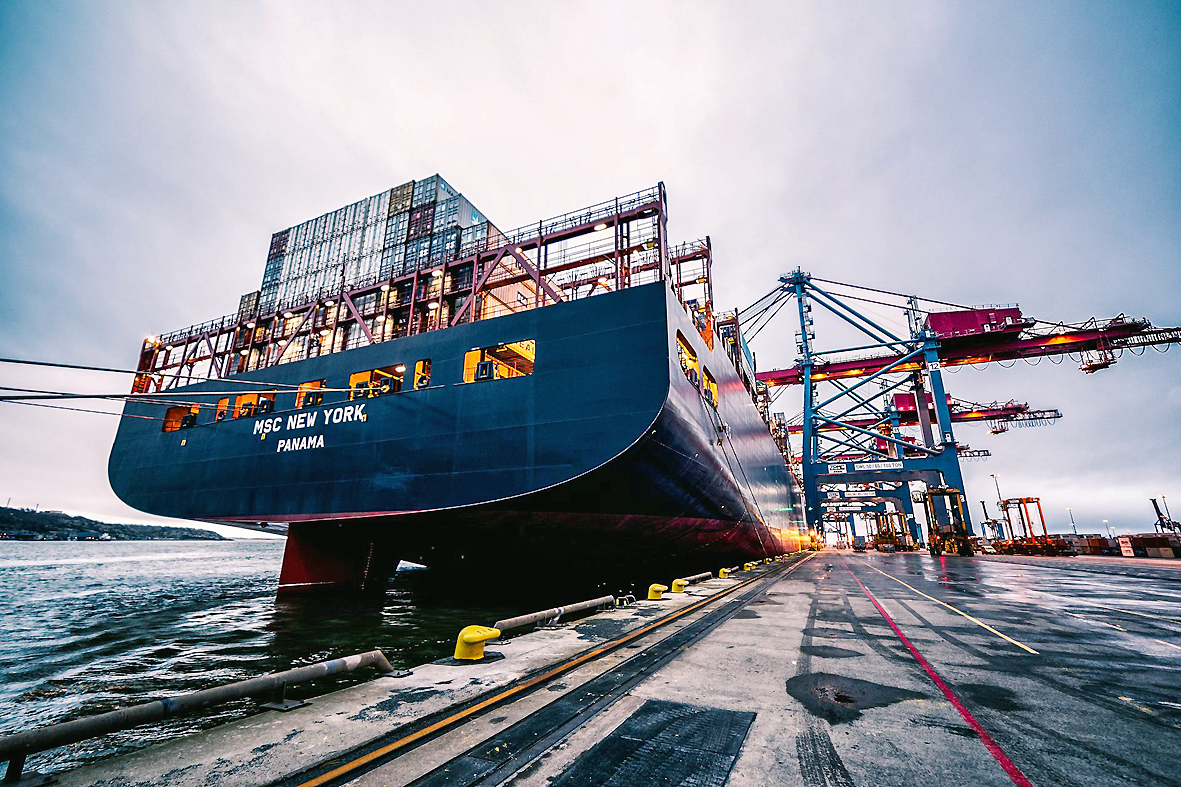 Maritime trends 2025_geo-trends.eu_Container ship docked at a modern port with loading cranes in the background during a cloudy day