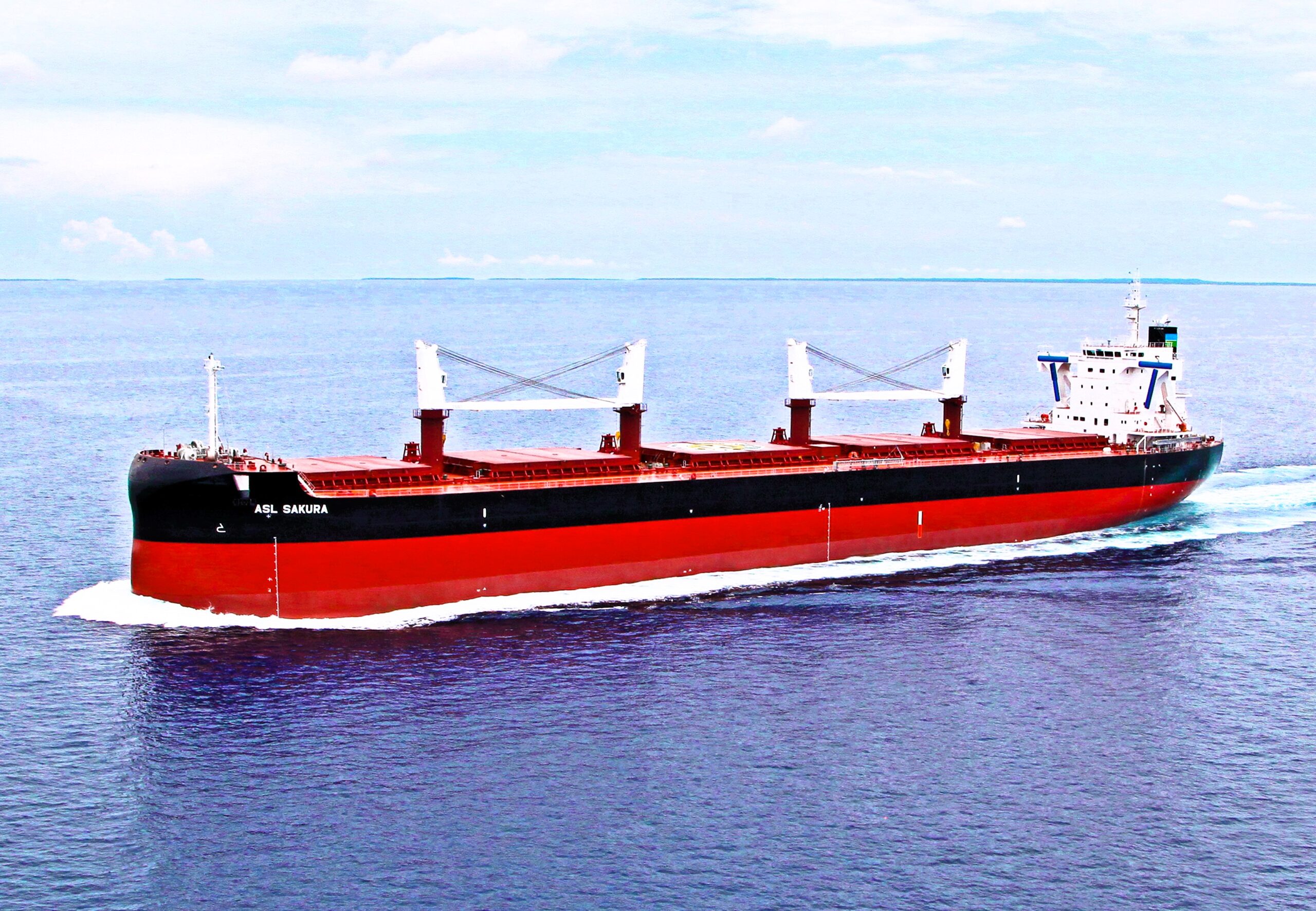 Red and black geared bulk carrier vessel ASL SAKURA sailing at sea with three white cranes on deck