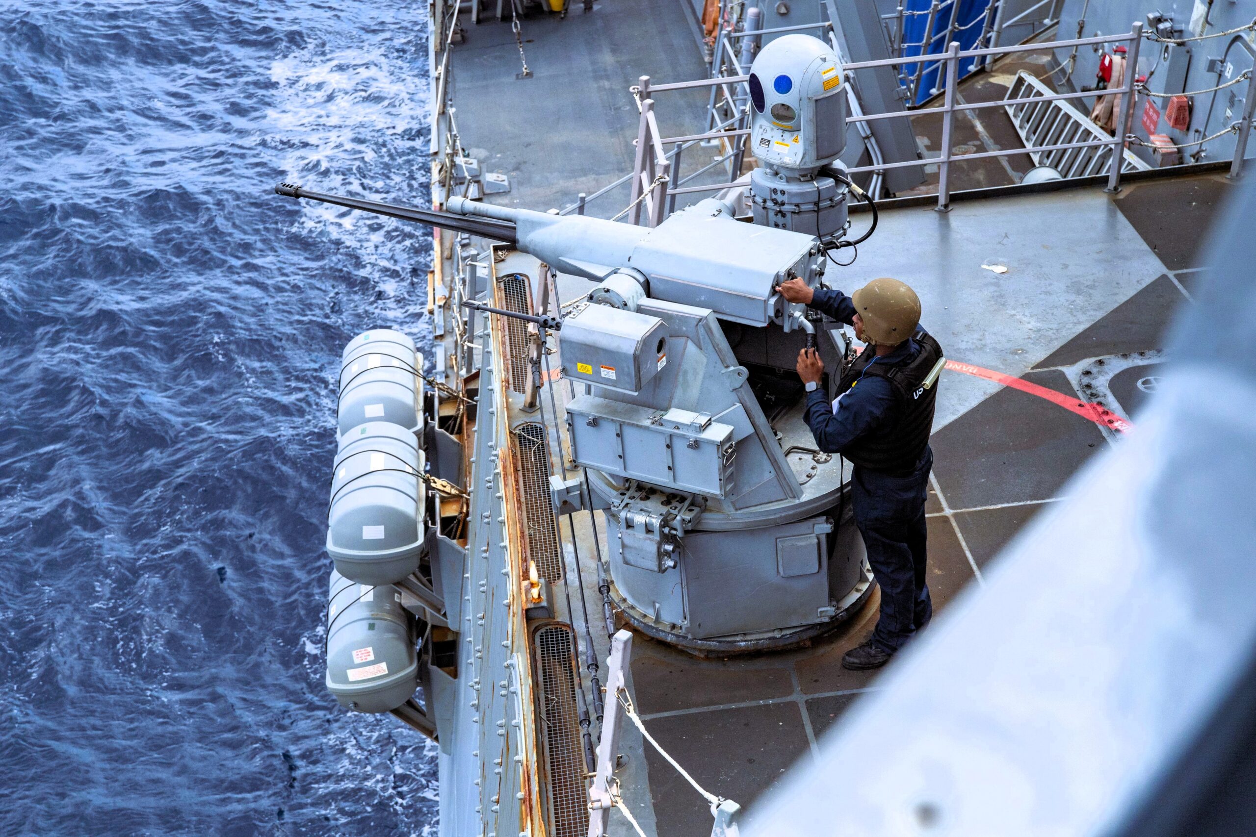 Naval crew member operating equipment aboard a warship at sea, symbolizing maritime readiness amid rising geopolitical tensions in the Caribbean