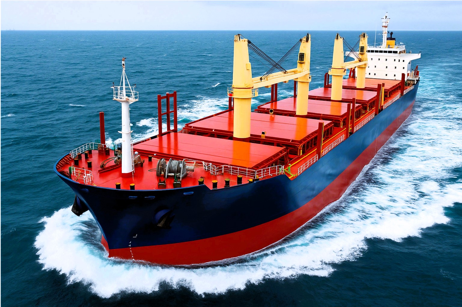 Ultramax bulk carrier with red hatch covers and deck cranes sailing at speed through open ocean waters