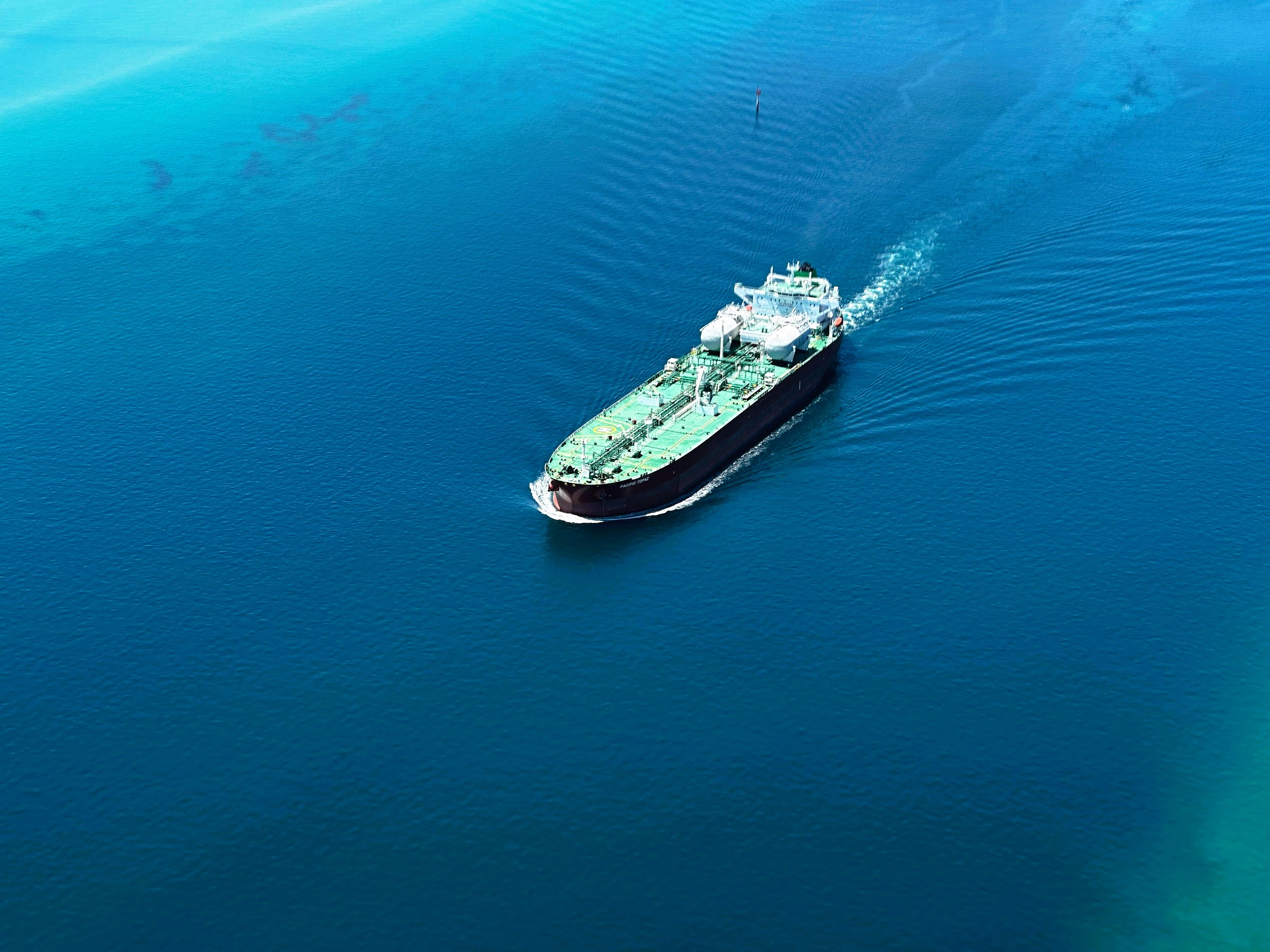 Aerial view of a large crude oil tanker underway across open blue sea, viewed from above