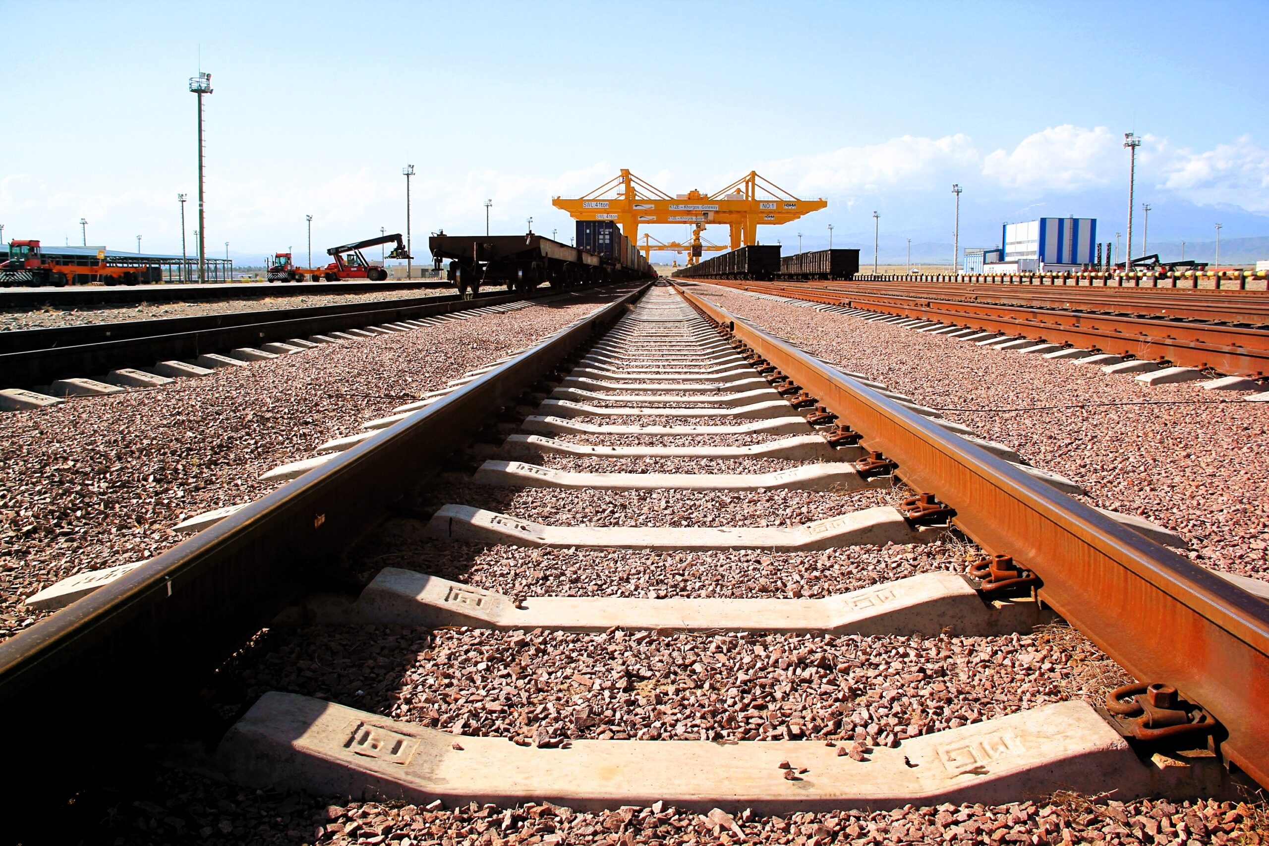 Railway tracks at KTZE Khorgos Gateway dry port leading toward container cranes, Central Asia corridor, Kazakhstan