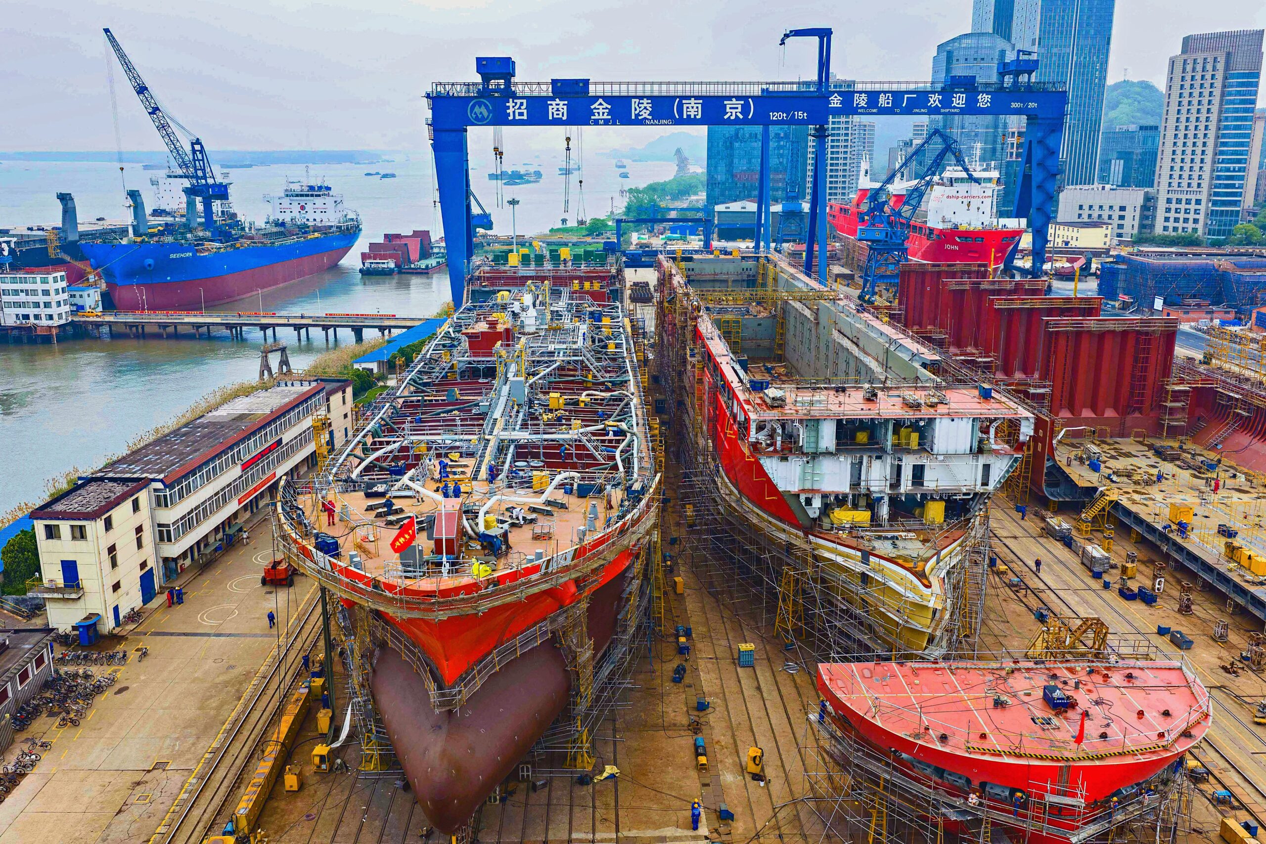 Aerial view of a large Asian shipyard where multiple commercial vessels are under construction in dry docks, illustrating strong global shipbuilding activity and fleet renewal