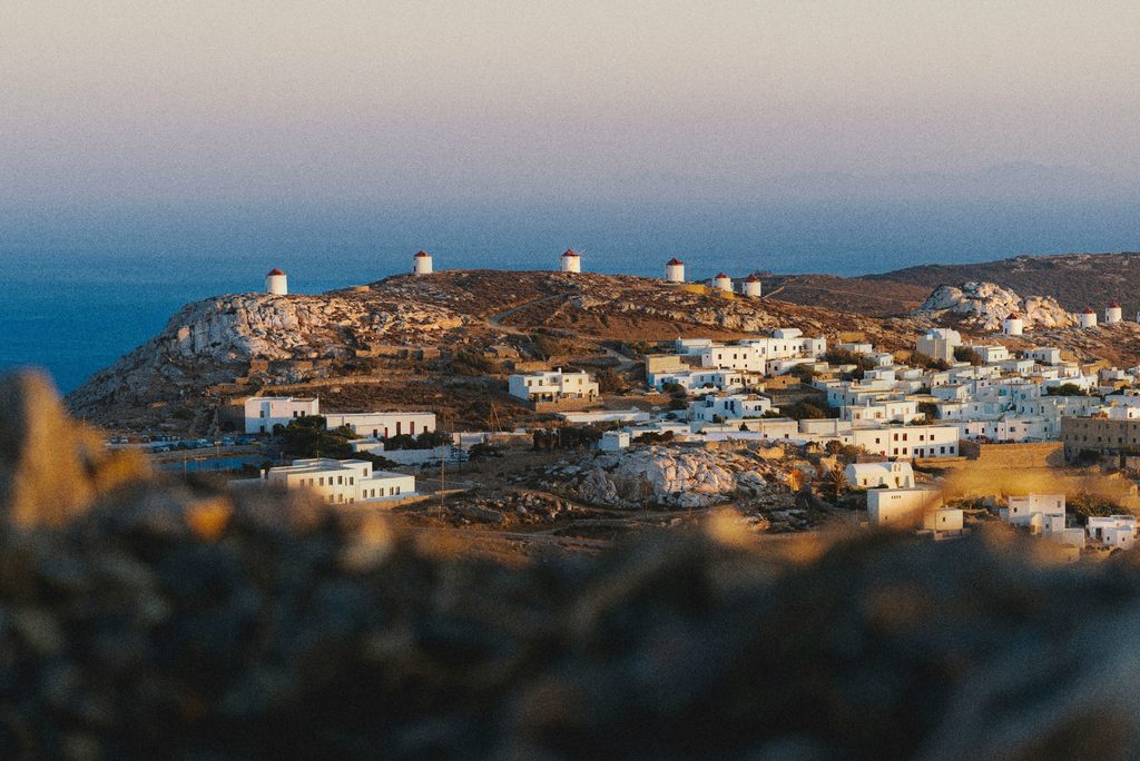Whitewashed Chora and its hilltop windmills spread across the rugged landscape of Amorgos, with the Aegean Sea beyond