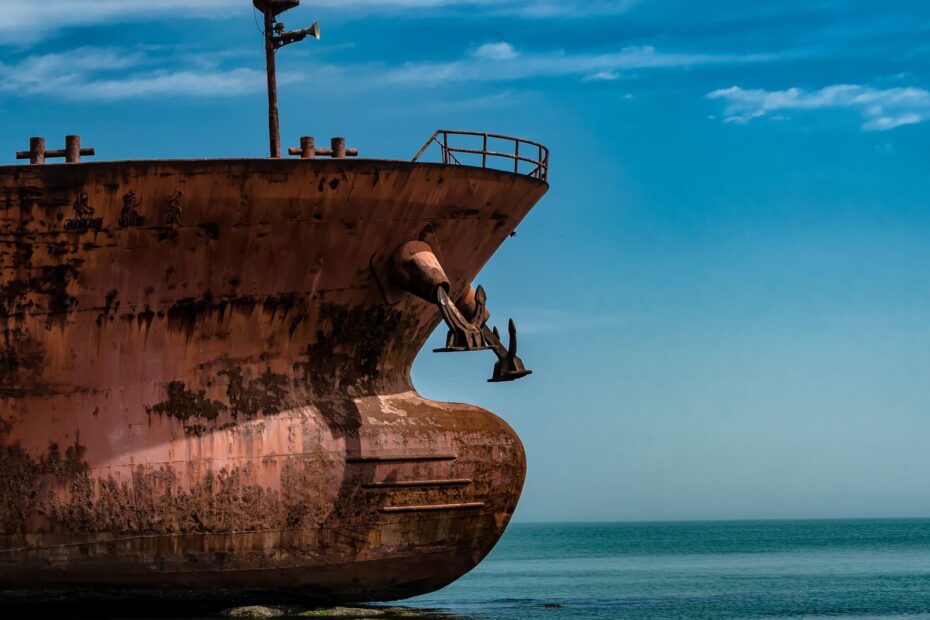 Rusted bow and anchor of a stranded cargo ship, illustrating maritime trade halted without dependable access